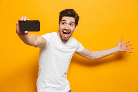 一个快乐的年轻人的肖像在黄色背景下用手机隔离 sefie