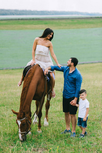 母亲骑马和父亲与儿子站在田野上