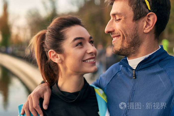 男人和女人在拥抱的时候互相微笑.跑步者在跑步后在外面休息