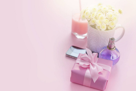 作文平躺礼物给一个女人。现代小玩意手机玻璃鸡尾酒香水花束的花朵。准备节日惊喜礼品盒。背景粉红色