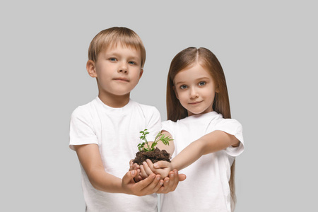 孩子们在工作室的背景下手上树苗。春天, 植物, 自然, 成长和关心概念。白种小女孩和男孩