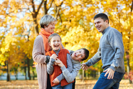 幸福的家庭在秋城公园散步。孩子们和家长摆姿势, 微笑, 玩耍和娱乐。明亮的黄色树