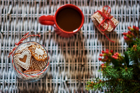 姜饼干在玻璃瓶里, 一杯热咖啡放在老白柳条的背景上。圣诞理念