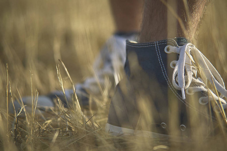 鞋在前景与后面的另一个同时被一个男孩走在草地上穿