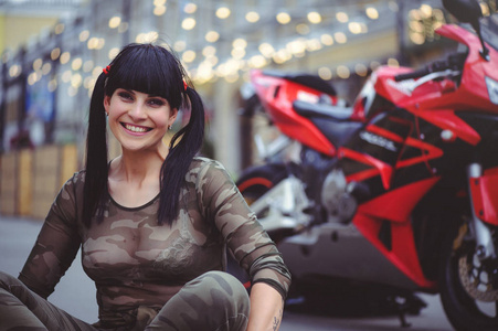 快乐的女子骑自行车坐在附近的摩托车和快乐, 特写黑发与红色的自行车