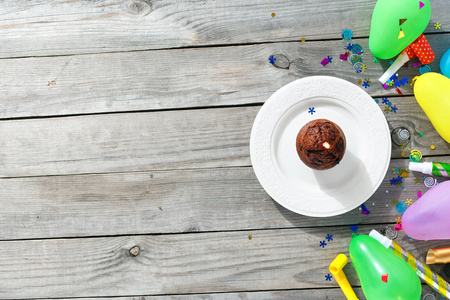 查看儿童生日表的概念。巧克力松饼蜡烛和装饰党在木质背景与复制空间平躺