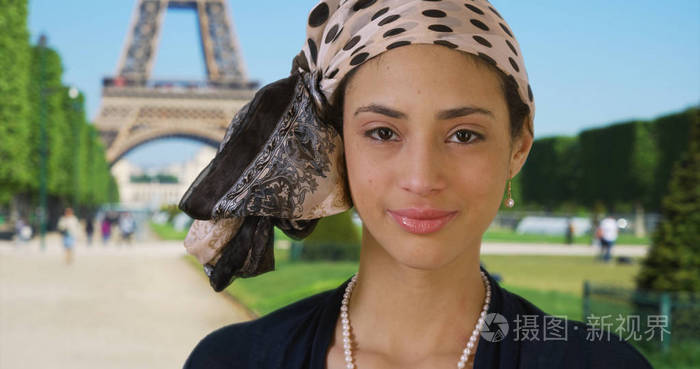 靠近站在埃菲尔铁塔附近的华丽微笑的拉丁妇女