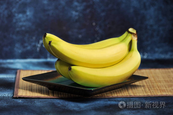 一束成熟的香蕉在一个深蓝色背景的盘子上