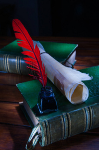 鹅毛笔和一卷纸莎草纸张与旧书木制的桌子上