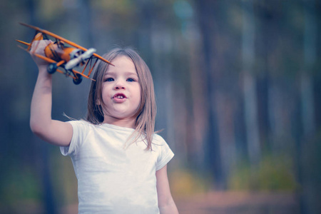 在户外玩玩具飞机的小女孩。旅行的梦想