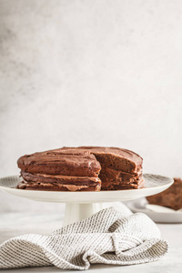 纯素巧克力蛋糕上的白盘子蛋糕, 浅色背景。健康素食食品概念