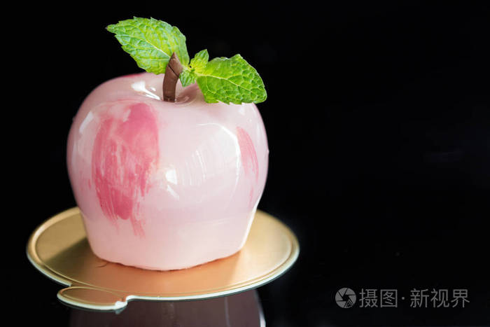 黑色背景下苹果形状的时尚粉红色镜面釉慕斯蛋糕