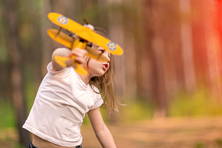 在户外玩玩具飞机的小女孩。旅行的梦想