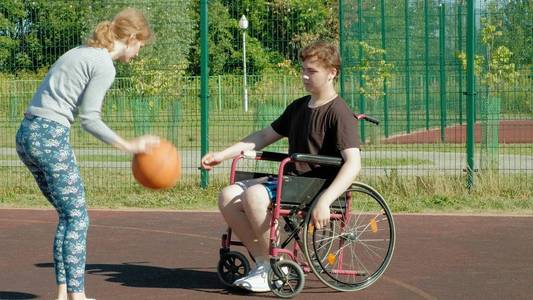 残疾人打篮球从他的轮椅与一个女人, 在露天, 努力时, 发挥