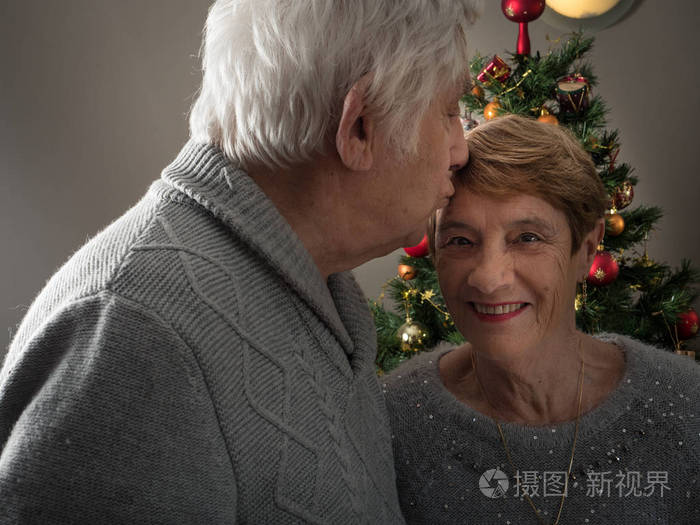 一对老情侣在圣诞树前接吻的特写protrait
