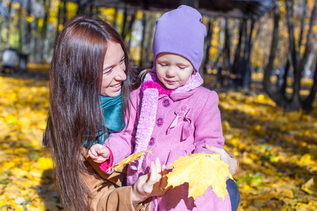 可爱的女孩和黄色秋天的树林，在一个温暖的晴天的幸福母亲的肖像