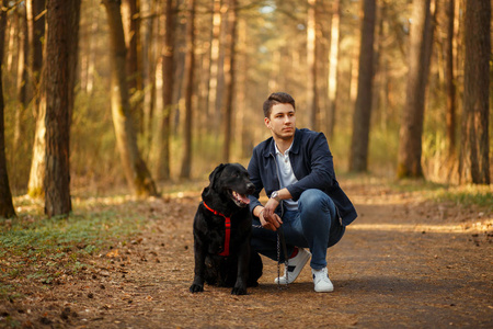 时髦的年轻人与狗在公园里在一个春天晴朗的天照片