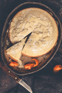 杏仁蛋糕上的深色菜, 顶部视图, 深色背景。橙色坚果馅饼