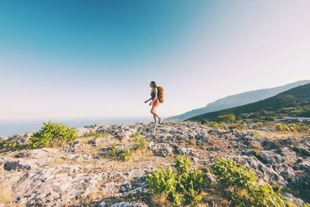 女孩在山顶上.一个背着背包的女人沿着一条山路走.爬上山顶.