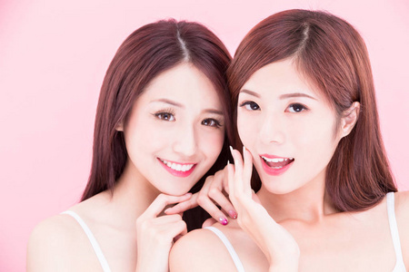 粉红色背景下的两个美容护肤妇女与健康牙齿