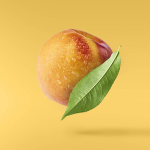 在黄色的背景下, 在绿色的叶子上飞行新鲜成熟的桃子。食品悬浮概念, 高分辨率图像
