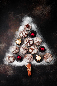 圣诞树由布朗尼饼干与裂缝, 肉桂香料, 铃铛和圣诞玩具在旧的混凝土或石材背景。新年的概念。顶部视图