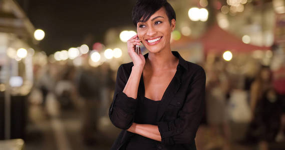 在户外晚间农贸市场用智能手机交谈和发短信的妇女