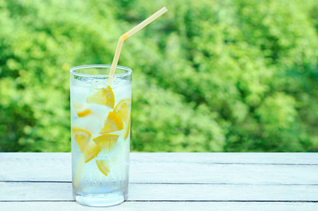 一只出汗的杯子, 里面有冰和柠檬的清爽鸡尾酒。在木质背景上