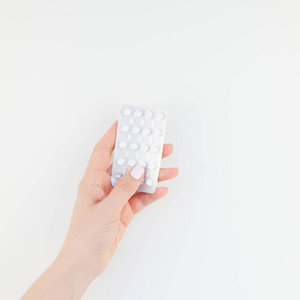 女人手用粉彩指甲抛光在白色背景与复制空间隔离的水泡药片。方形模板为女性美女博客社交媒体。女性保健理念