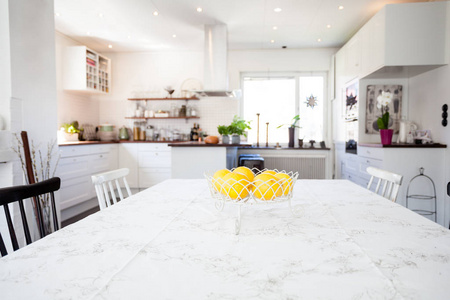 新鲜柠檬在玻璃碗在晚餐桌与厨房在背景上