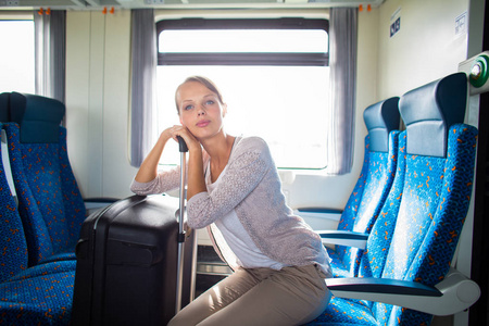一位年轻漂亮的女士带着她的大后备箱坐火车旅行
