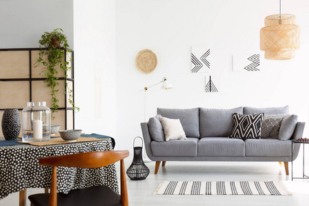 明亮舒适的起居室的真实照片灰色沙发上有图案的枕头和餐桌上的木椅
