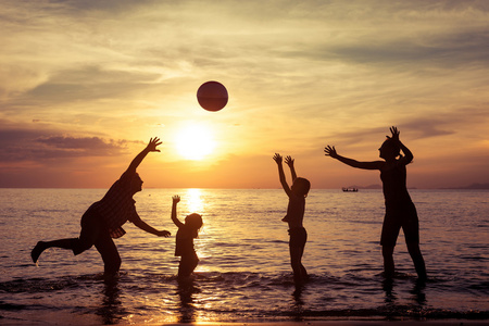 幸福的家庭的剪影在一元在沙滩上玩的人