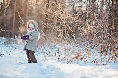 可爱的孩子女孩在白雪皑皑的冬天阳光森林举行雪上行走
