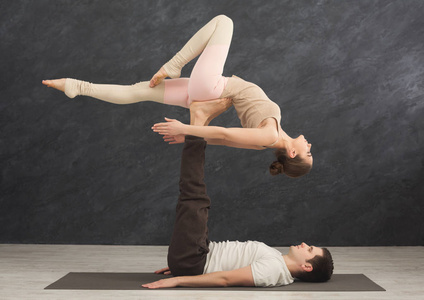 年轻夫妇在垫子上练习 acroyoga