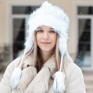 美丽的女孩在冬季夹克站在房子附近
