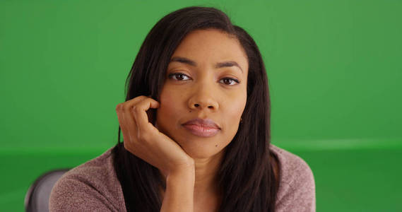 关闭可爱的黑色女性休息的手在下巴下的绿色屏幕上的肖像