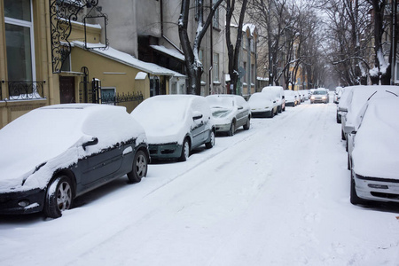 城市街道在暴风雪以后。被雪覆盖的汽车