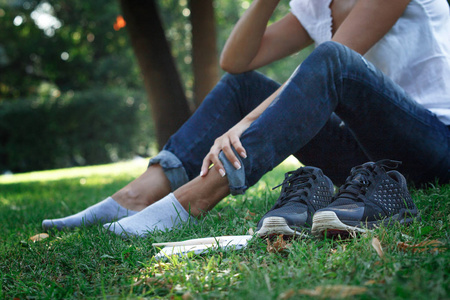 女孩脱掉鞋子, 赤脚躺在公园的草地上.