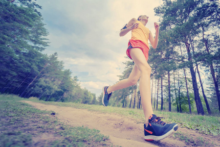 在公园慢跑的女跑步者.女孩在户外训练.在森林小径上锻炼.