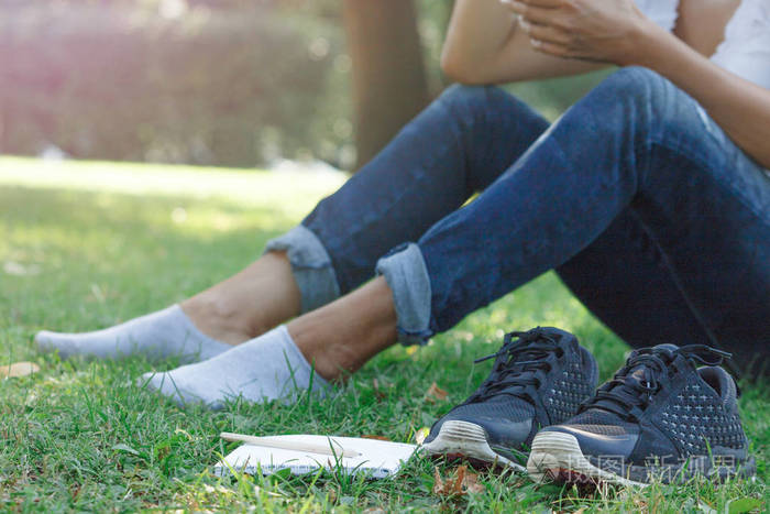 女孩脱掉鞋子赤脚躺在公园的草地上记事本和铅笔创造性思维的概念和