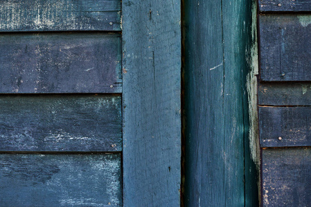 木墙绿色和蓝色油漆严重风化和剥落。漆木墙开裂。木板条质朴简陋的空背景。油漆去皮风化表面。垃圾幕墙壁纸