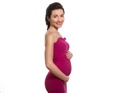 白种人微笑着怀孕的姑娘动人美声的粉红色连衣裙