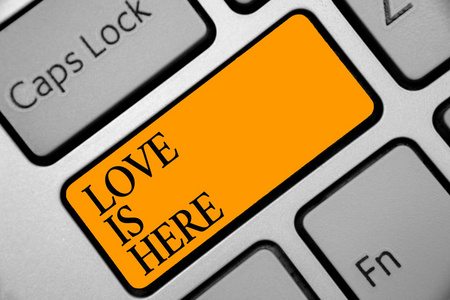 概念性手写显示爱在这里。商务照片展示浪漫感觉可爱的情感积极表达关怀喜悦键盘橙色键计算机计算反射文档