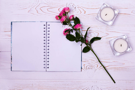 空白笔记本, 花, 蜡烛上的白色背景从上面。平面造型。复制文本空间