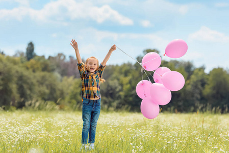 快乐的孩子与粉红色气球在夏天领域