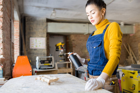 现代年轻女子的腰部纵向喷漆木材在木工车间工作