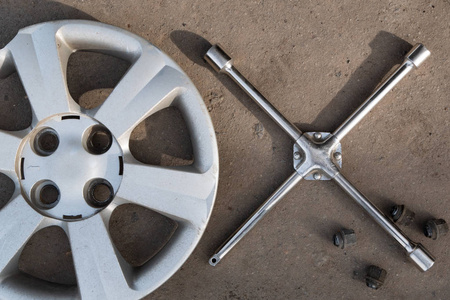 车轮盖, 冠扳手和四个螺丝躺在地上。轮胎更换车轮固定维修服务理念。从顶部的平面视图
