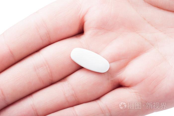 与手掌上的一个白色药片特写