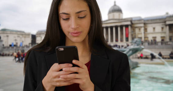 在伦敦特拉法加广场, 微笑着的拉丁女商人在手机上发短信